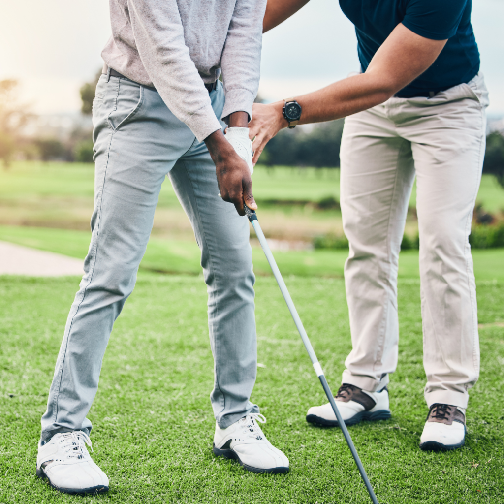 A golf instructor teaching a beginner how to grip a golf club